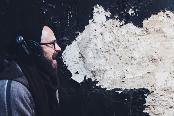 Man against wall with chipped paint in shape of speech bubble